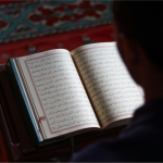 Person reading Quran at sunrise